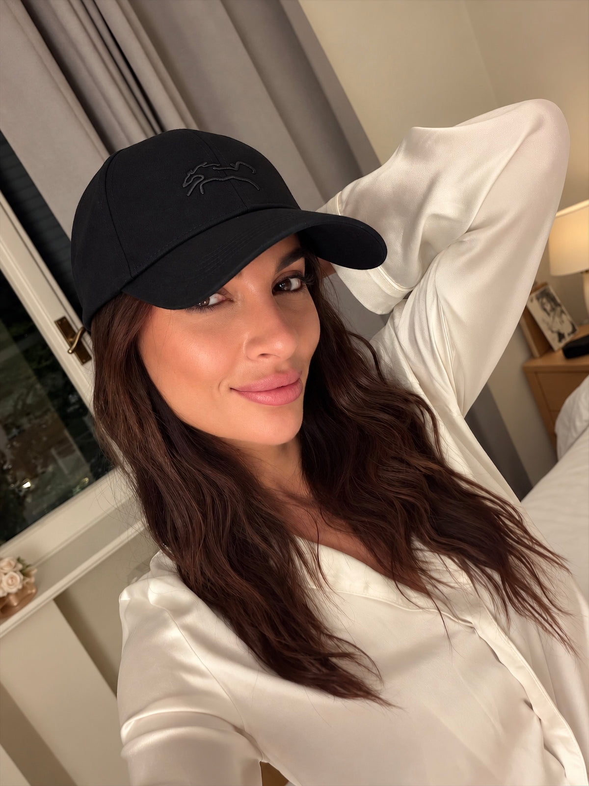 A person wearing the Core Cap, a black baseball cap, indoors.